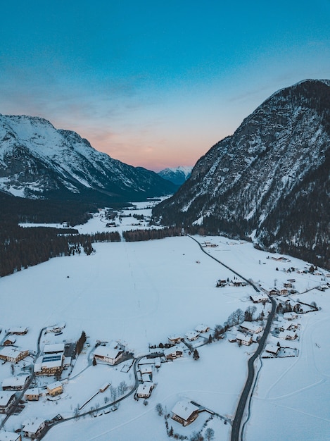 Photo à couper le souffle d'une chaîne de montagnes avec une ville en dessous en hiver au coucher du soleil