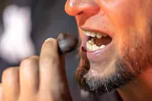 Photo gratuite une photo détaillée de la bouche d'un homme qui mord un bonbon au chocolat