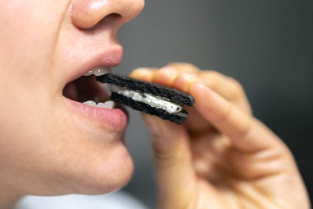 Une photo détaillée d'une femme mordant un biscuit au chocolat.