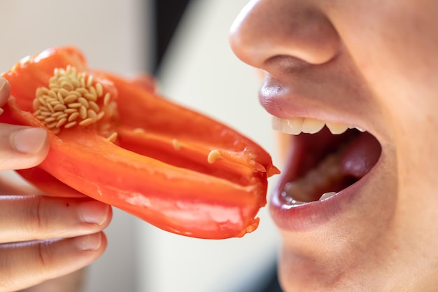 Une photo détaillée d'une femme mordant du poivre rouge