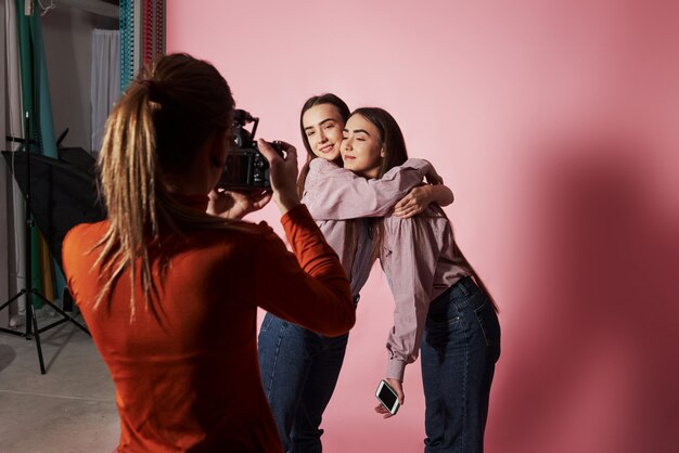 Photo de deux filles qui s'embrassent et sont photographiées par une caméraman dans le studio