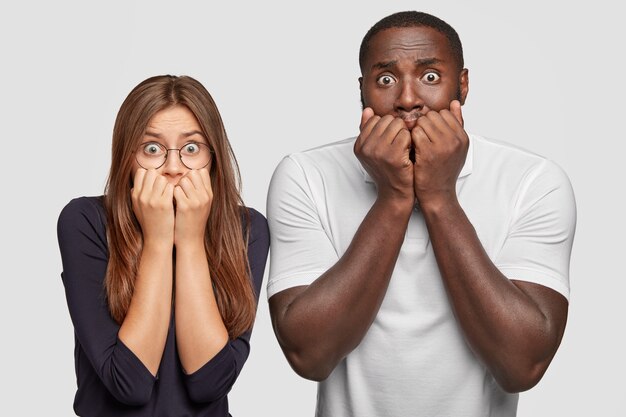 Photo de deux homme et femme interraciaux étonnés et perplexes tremblent de peur