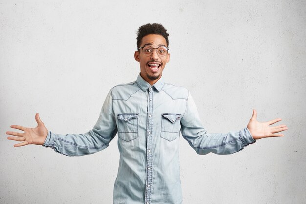 Photo d'un employé masculin talentueux qui fait des gestes actifs, a une expression heureuse et excitée après avoir obtenu une promotion au travail