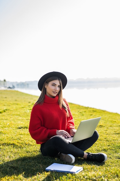 Une photo d'un étudiant utilisant un ordinateur portable sur l'herbe du campus