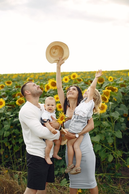 Photo de famille heureuse. Parents et fille. Famille ensemble dans le champ de tournesol. Homme en chemise blanche.