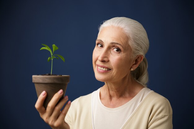 Photo d'une femme âgée joyeuse tenant une jeune plante sur place