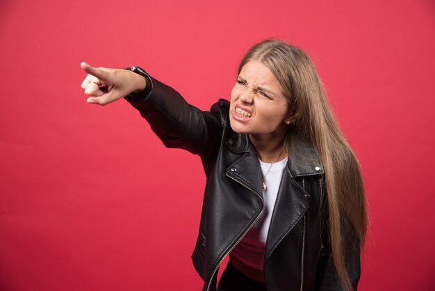 Photo de femme en blouson de cuir pointant vers l'extérieur