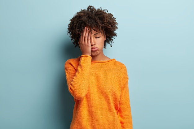 La photo d'une femme fatiguée à la peau foncée couvre le visage, ferme les yeux, ressent de la fatigue, a besoin d'un bon repos