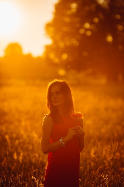 Photo d&#39;une femme magnifique en robe rouge se tenant dans un champ doré