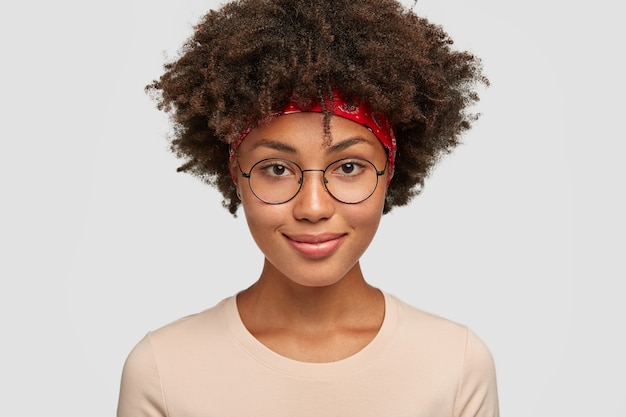 Photo de femme à la peau foncée joyeuse à la recherche agréable dans des lunettes rondes