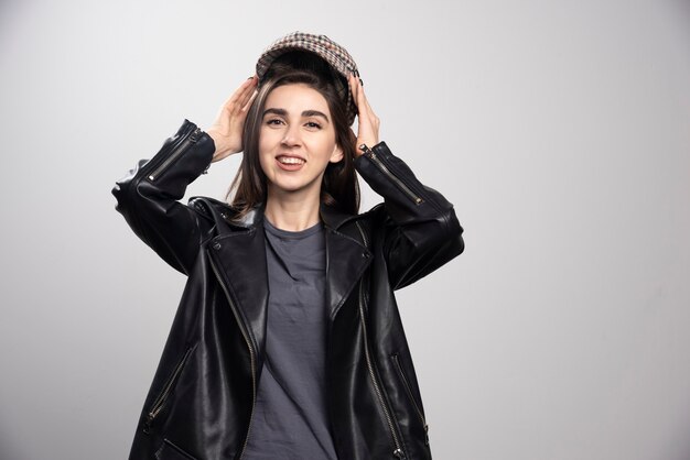 Photo d'une femme posant dans une veste en cuir noir et une casquette.