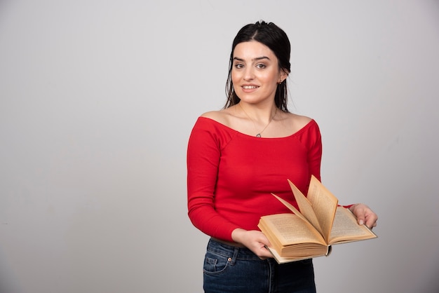 Photo gratuite photo d'une femme souriante debout et posant avec un livre ouvert.