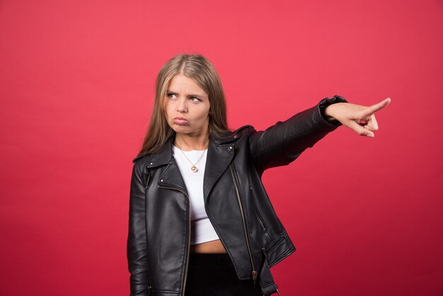 Photo de femme en veste de cuir pointant vers l'extérieur et donnant la direction