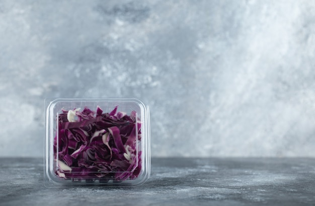 Photo gratuite photo grand angle d'un récipient en plastique plein de chou violet haché sur fond gris.