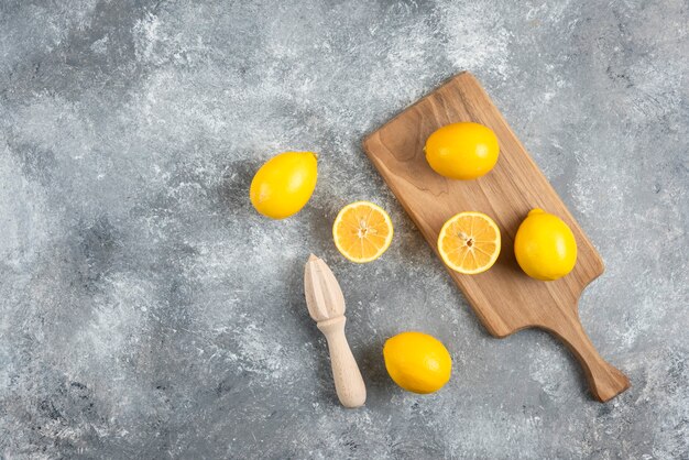 Photo grand angle de tas de citrons sur planche de bois et sol.