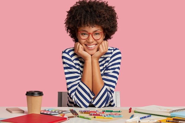 Photo gratuite photo d'un graphiste à la peau sombre souriant satisfait d'être de bonne humeur