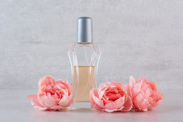 La photo en gros plan de la bouteille de parfum avec des fleurs.