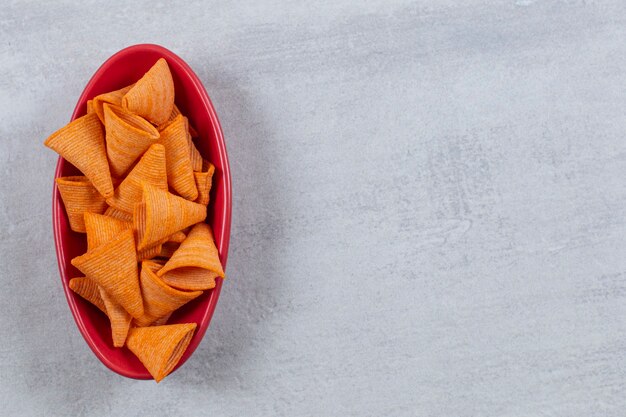 La photo en gros plan de chips épicées dans un bol rouge.