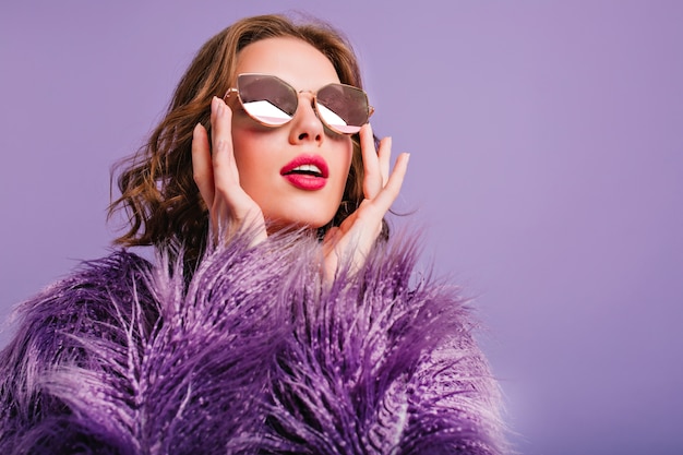 Photo en gros plan d'une femme à la mode inspirée dans des verres scintillants regardant avec la bouche ouverte