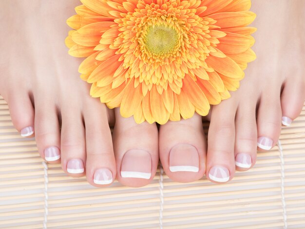 Photo gros plan d'une femme pieds avec pédicure française blanche sur les ongles