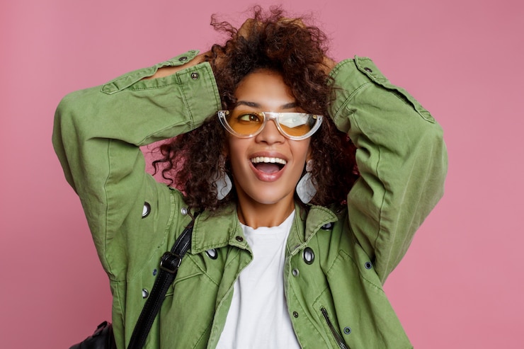 Photo gratuit la photo en gros plan d'une incroyable fille africaine bouclée sur fond rose. portant une veste tendance verte.