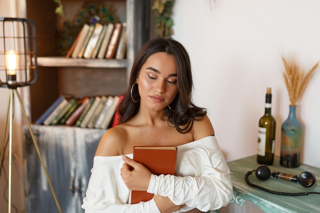 Photo en gros plan d'une jeune femme tenant son livre et assise sur une chaise à la réception Photo de haute qualité