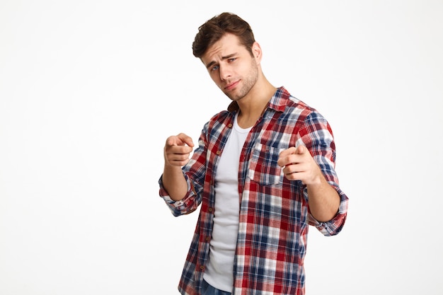 Photo en gros plan d'un jeune homme sérieux en chemise à carreaux pointant avec deux doigts