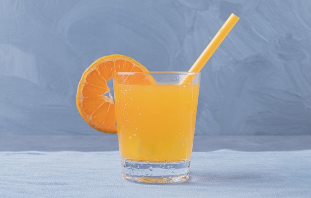 Photo gratuite la photo en gros plan de jus d'orange fraîchement préparé sur fond gris.
