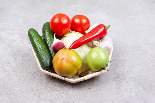 La photo en gros plan de légumes biologiques frais dans le panier sur une surface grise.