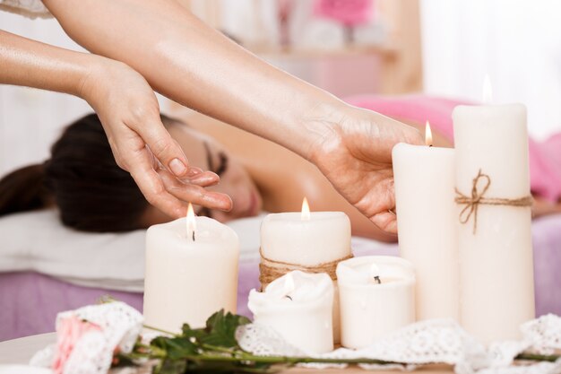 Photo gros plan de mains féminines prenant des bougies au salon spa