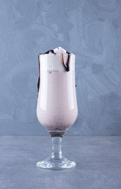 La photo en gros plan de milk-shake au chocolat fraîchement préparé sur fond gris.