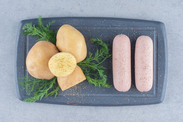 La photo en gros plan de pommes de terre bouillies épicées et saucisses