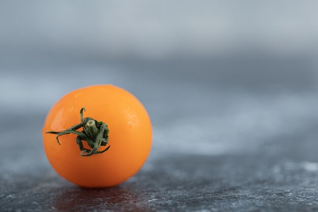 La photo en gros plan de la tomate cerise jaune fraîche sur fond gris.