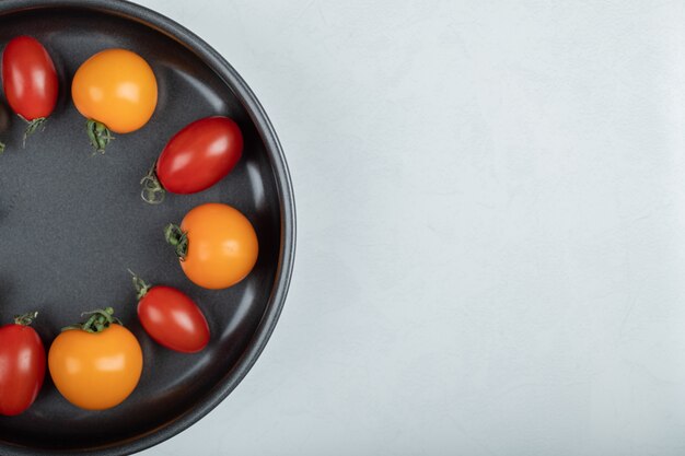 La photo en gros plan de tomates cerises colorées dans la casserole sur fond blanc. Photo de haute qualité