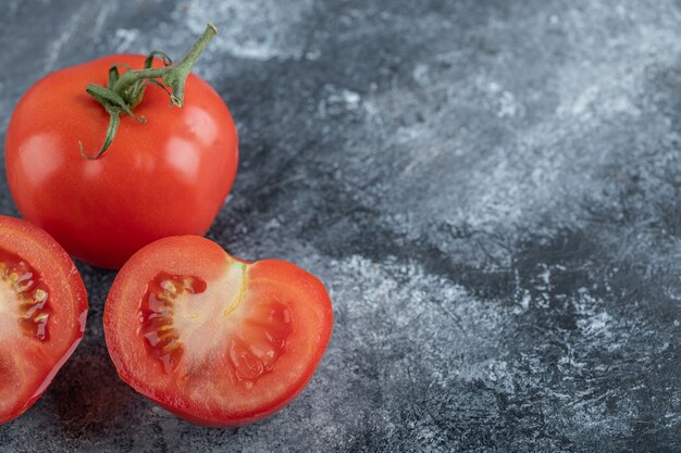 La photo en gros plan de tomates fraîches rouges entières ou coupées. Photo de haute qualité