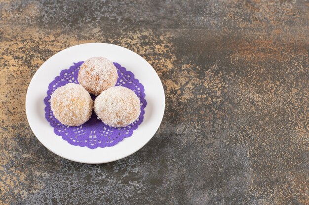 La photo en gros plan de trois biscuits faits maison frais sur plaque blanche.