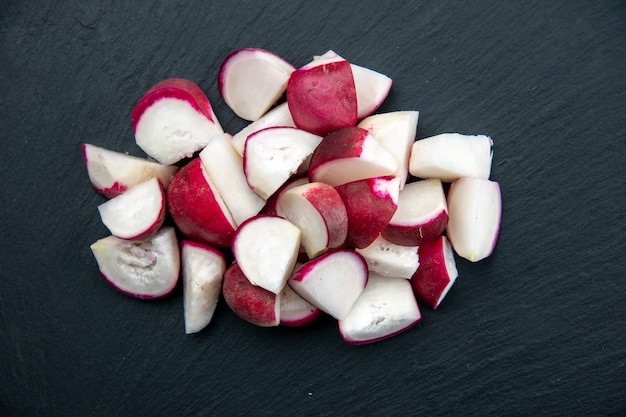 Photo haute résolution de radis frais hachés sur une planche à découper de couleur foncée