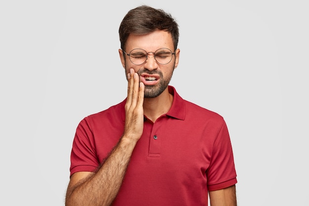 Photo d'un homme de race blanche souffre de maux de dents douloureux, a une dent pourrie, doit consulter un dentiste