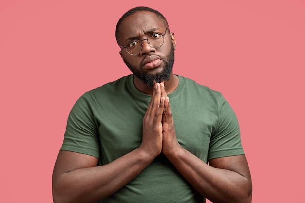 Photo D'un Homme Sérieux Avec Une Expression Implorante, Maintient Les Paumes Jointes, Demande Quelque Chose à Son Amant