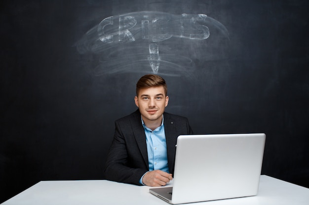 Photo d'un homme souriant sur tableau noir avec inscription de crise