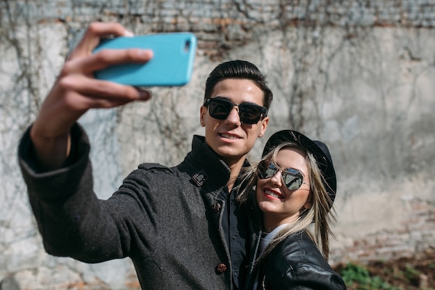 Photo d'un jeune beau couple faisant selfie sur mur gris