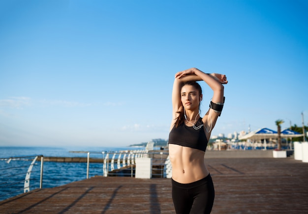 Photo de jeune belle fille de remise en forme fait des exercices de sport avec la côte de la mer