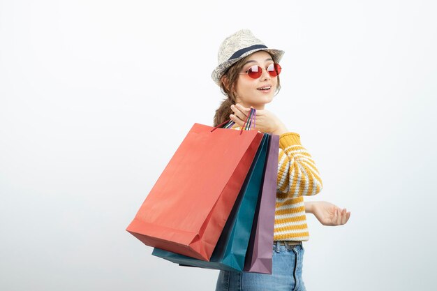 Photo de jeune femme brune à lunettes de soleil tenant des sacs à provisions. Photo de haute qualité