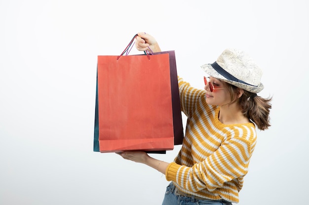 Photo de jeune femme brune à lunettes de soleil tenant des sacs à provisions. Photo de haute qualité