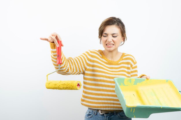 Photo d'une jeune femme debout tenant un rouleau à peinture dans sa main. Photo de haute qualité