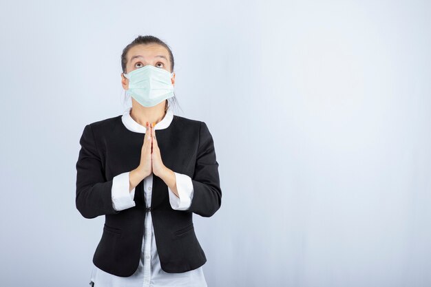 Photo de jeune femme en masque priant sur fond blanc. Photo de haute qualité