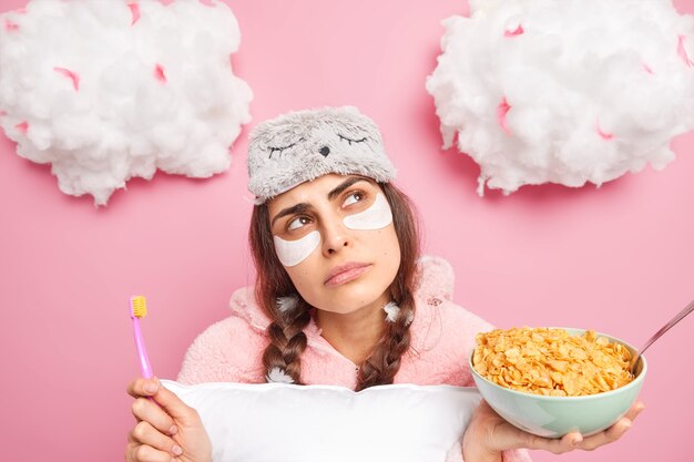 La photo de la jeune femme réfléchie a deux nattes avec des plumes a le petit déjeuner