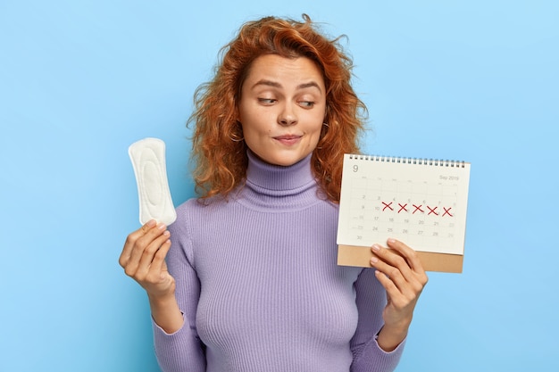 Photo gratuite photo de jeune femme regarde le calendrier des règles, vérifie les jours de menstruation