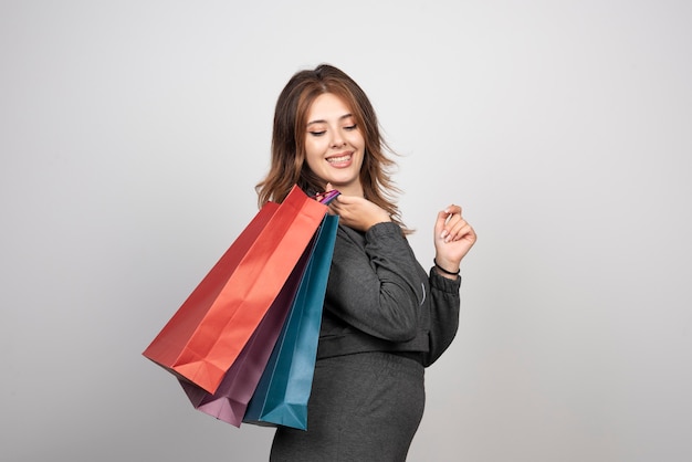 Photo de jeune femme avec des sacs à provisions et agitant la main.