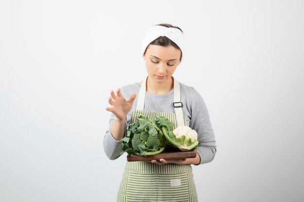 Photo d'une jeune femme séduisante tenant une assiette en bois de chou-fleur et de brocoli